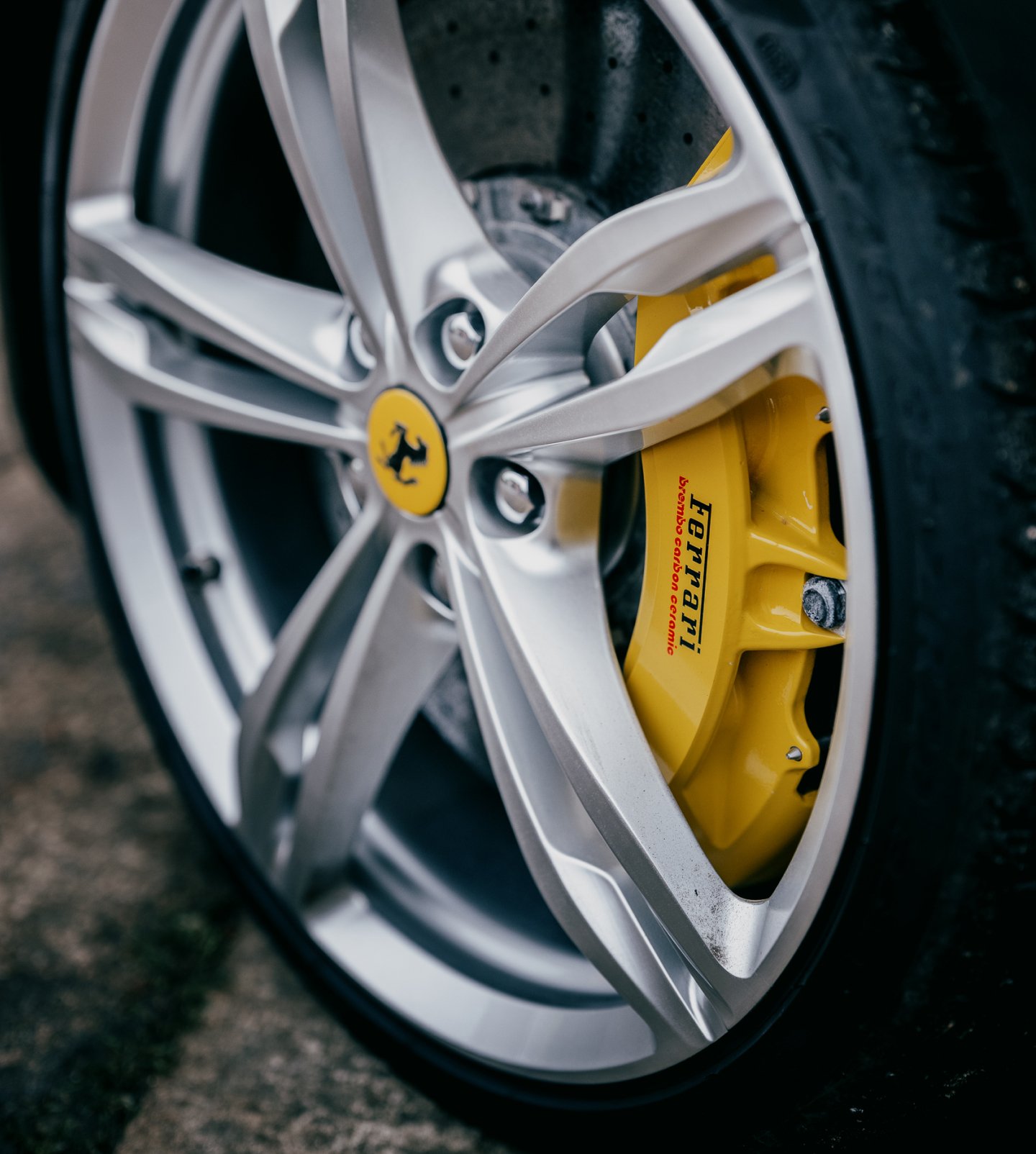A close up of the a ferarri allow wheel with bright yellow brake callipers. The text Ferarri is clearly visible.